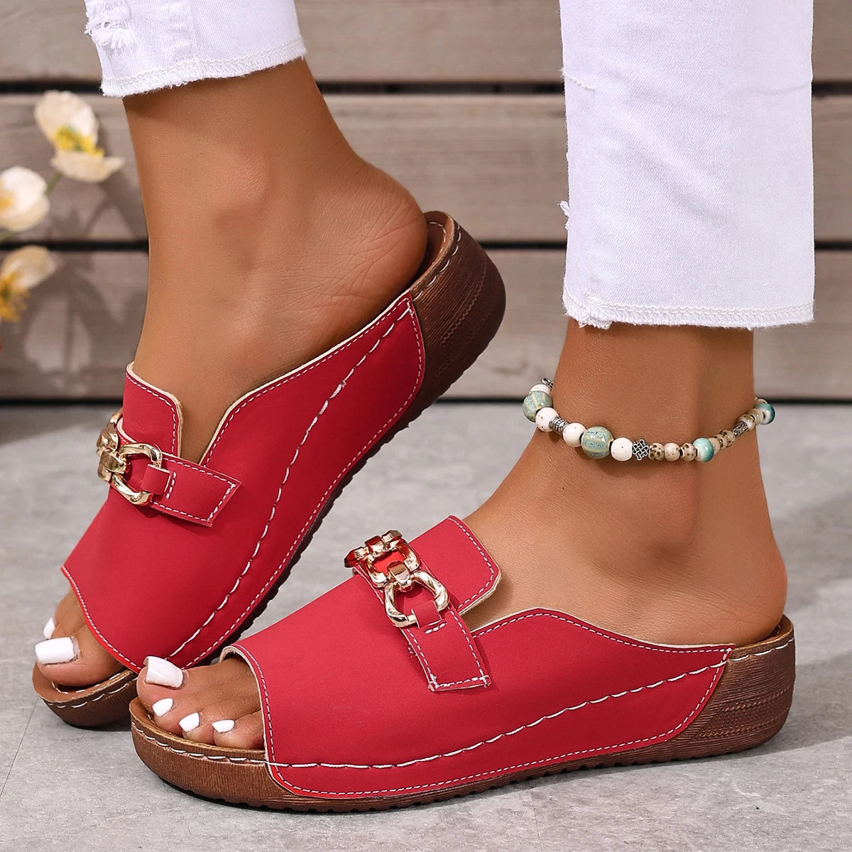 Red open-toe sandals with brown soles worn by a person on a neutral background