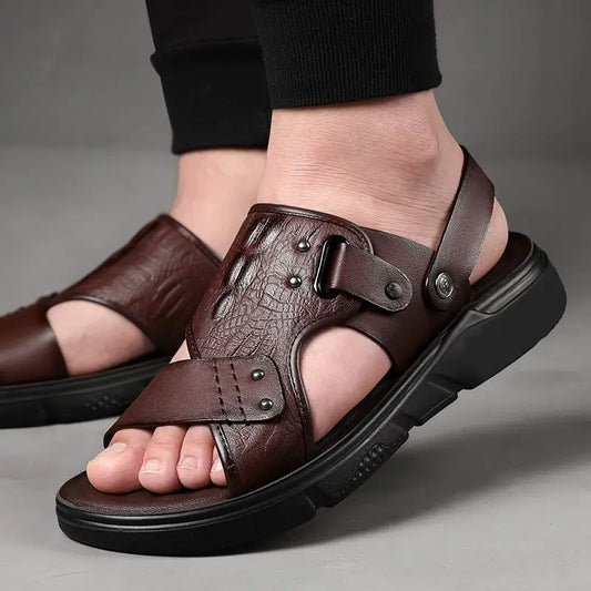 Brown leather sandals worn by a person on a gray background